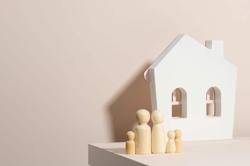 A wooden family and house figurine in the concept of moving to a new apartment